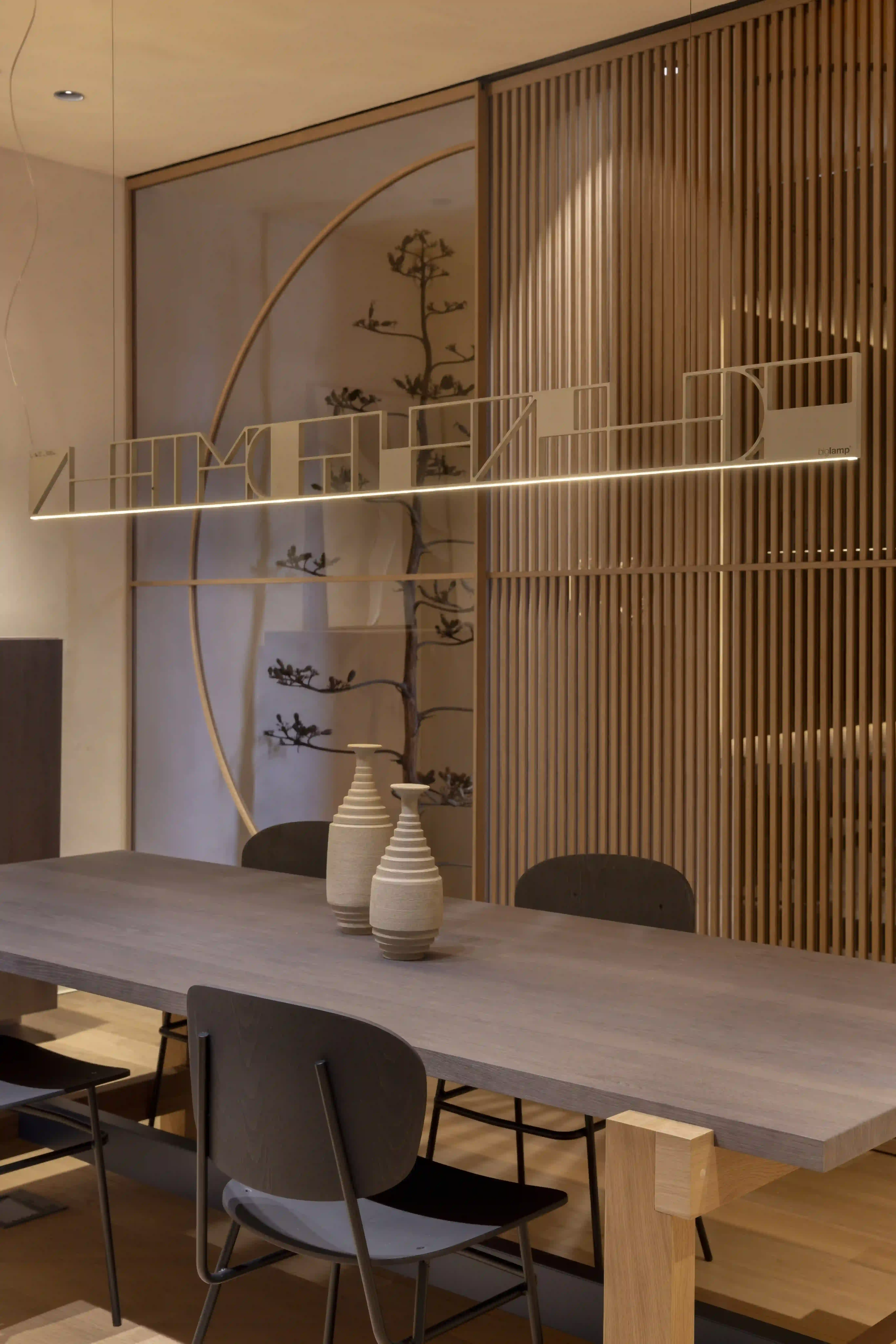 Comedor contemporáneo con mesa de madera, separador de lamas e iluminación decorativa<br />
